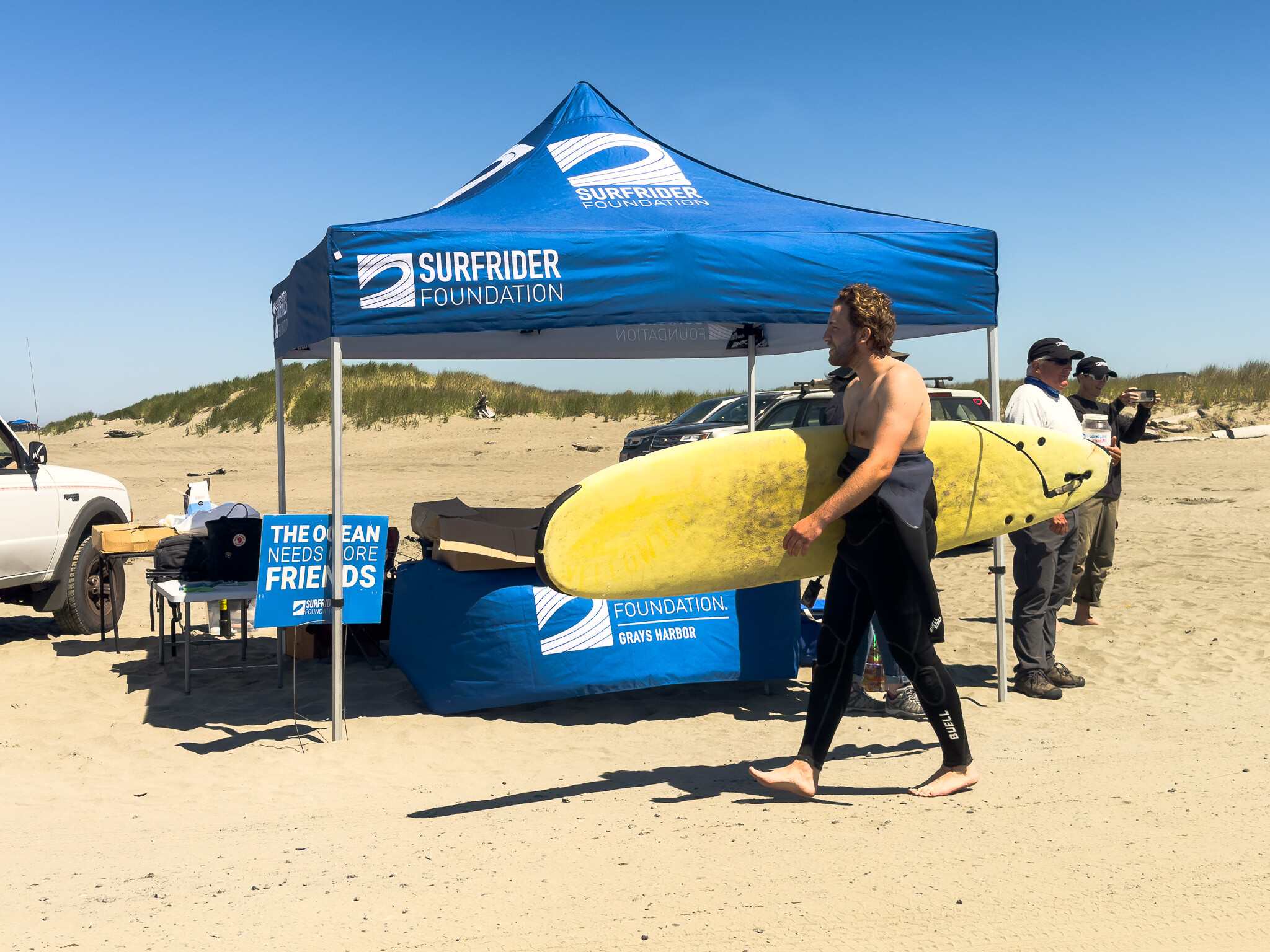 Surfer walking by Surfrider Tent at BCU-3